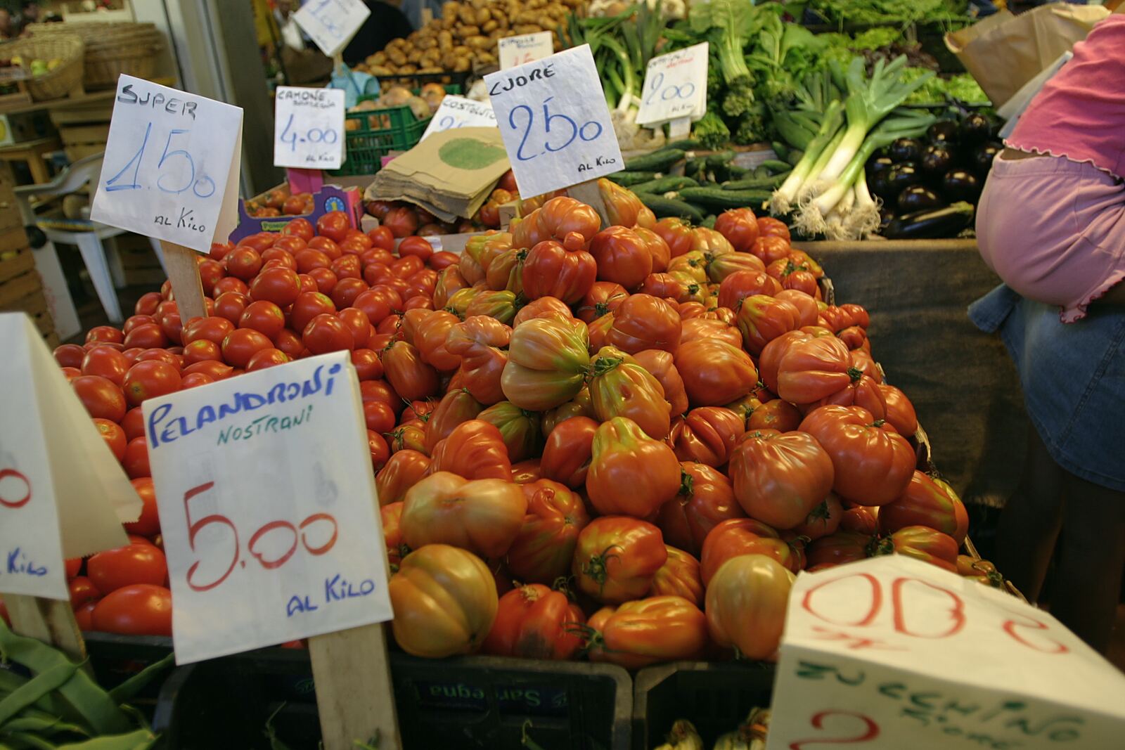 Pomodori sul banco di un mercato, con i prezzi scritti a mano