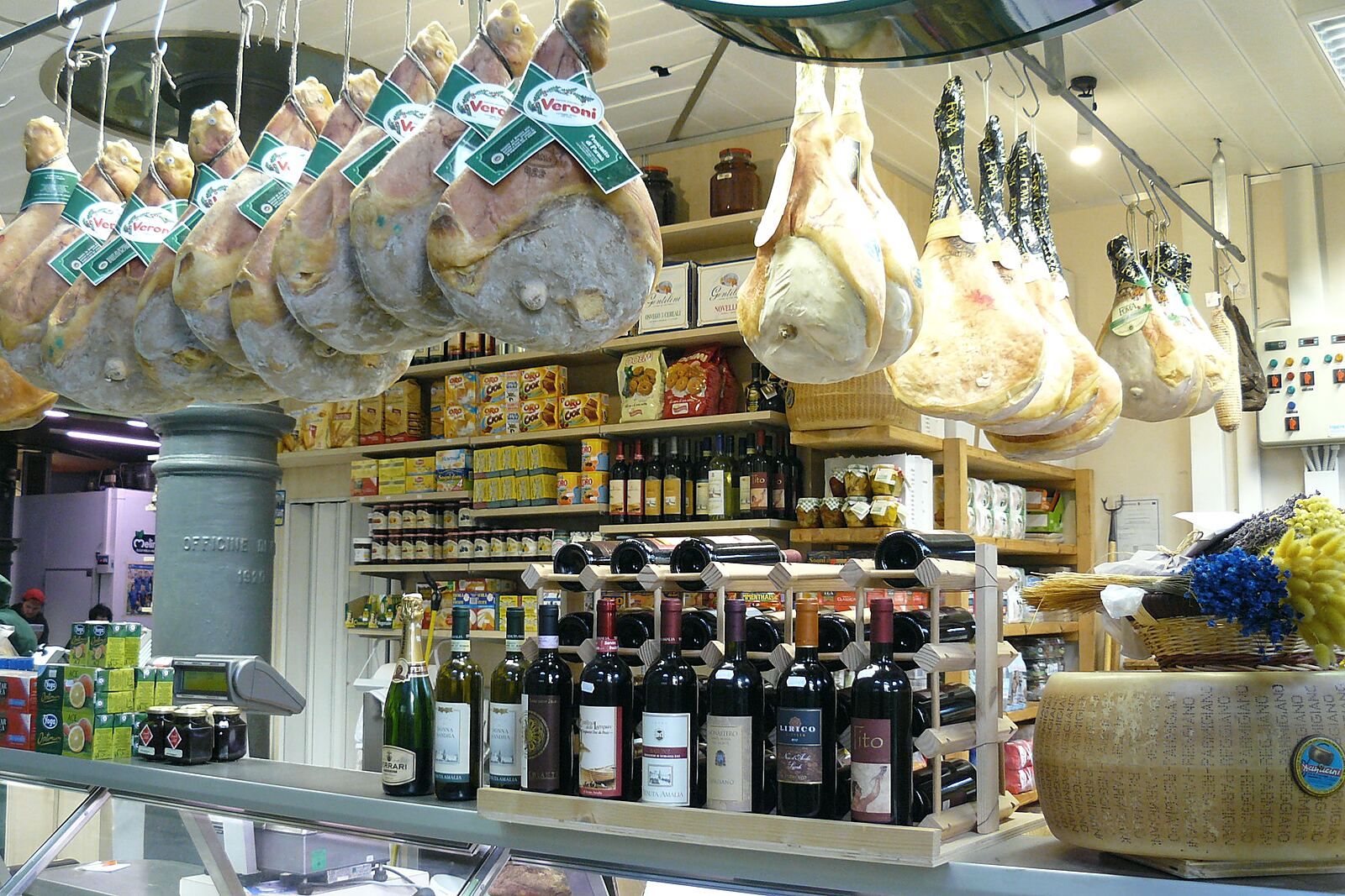 Prosciutti appesi e scaffali di vini in una bottega di gastronomia